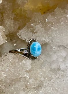 "See all pictures to see the variations in the stones. A beautiful oval cabochon Larimar with two white sapphire on each side set in Sterling silver. Larimar can come in a variety of blue colors often described as \"sky\" blue or \"swimming pool\" blue and can have streaks of light and dark blue or white just like a swimming poor the sky. This stone is 9x8 mm. I have ring sizes of US 5,6,7,8,9 A highly effective stone of the Throat Chakra, Larimar assists in communicating emotions and boundaries Blue Larimar Round Rings, Elegant Blue Larimar Rings, Blue Larimar Cabochon Rings, Oval Moonstone Larimar Ring, Oval Blue Larimar Jewelry, Blue Oval Moonstone Ring With Polished Finish, Blue Oval Opal Ring With Polished Finish, Oval Blue Moonstone Ring With Polished Finish, Elegant Oval Larimar Rings