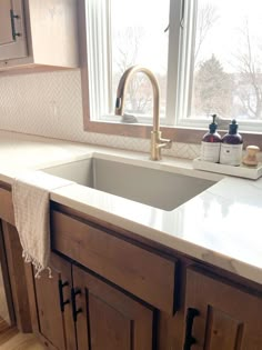 a kitchen sink sitting under a window next to a counter