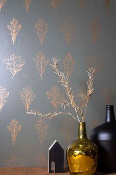 two vases sitting next to each other on top of a wooden table in front of a wall