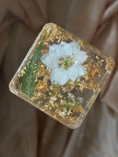 a white flower sitting on top of a piece of glass with gold flakes around it