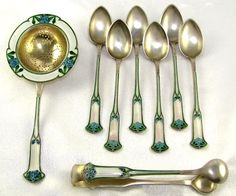 six silver spoons, one with blue and green designs on them