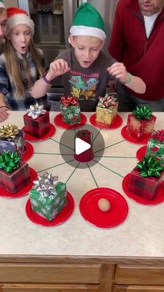 a group of people sitting around a table with presents on it and one person standing in front of the table