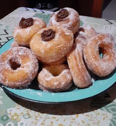 a blue plate topped with donuts covered in powdered sugar and chocolate toppings