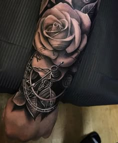 a man's arm with a rose and clock tattoo design on it, in black and white