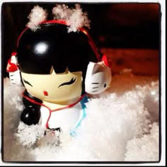 there is a small toy that looks like a girl with headphones in the snow