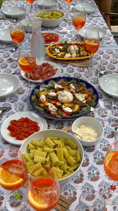 a long table with many plates and bowls of food on it, including oranges