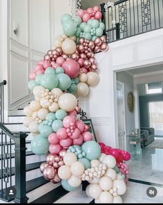 the staircase is decorated with balloons and streamers in pastel colors for a party