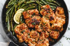 shrimp in a skillet with lemon wedges and parsley on the side for garnish