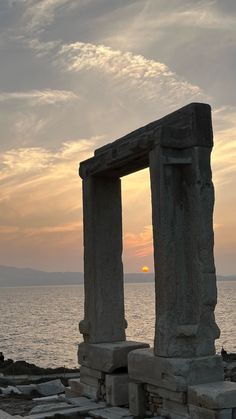 the sun is setting behind two stone pillars