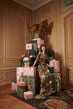 a woman sitting on top of a pile of wrapped presents in front of a wall