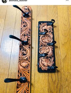 two black handles on a wooden floor with an intricate design and metal clips attached to them