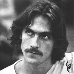 a black and white photo of a man with long hair wearing a moustache