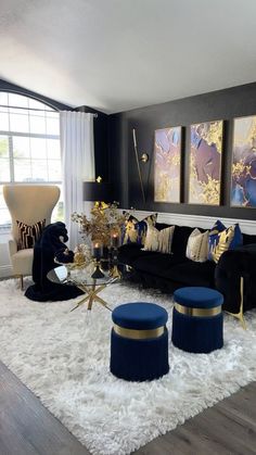 a living room filled with black couches and blue ottomans on top of a white rug