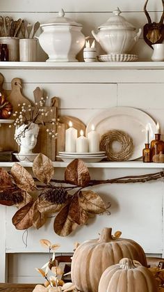 a table topped with lots of white pumpkins and other fall decorating items on top of shelves