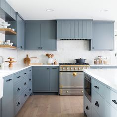 a kitchen with blue cabinets and white counter tops is pictured in this image, the stove has gold knobs on it