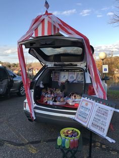 an open trunk with food and drinks on the back in a parking lot next to parked cars