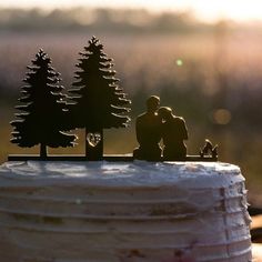 the cake is decorated with figurines of people and trees