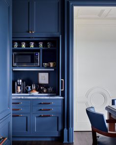 a kitchen with blue cabinetry and wooden flooring, along with a dining room table