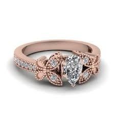 a rose gold engagement ring with two pear shaped diamonds on the sides and an oval center stone