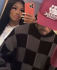 a woman taking a selfie with a man wearing a pink hat and black sweater