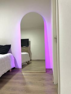 a room with a bed, mirror and purple light on the wall in front of it