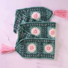 two crocheted bags with tassels on them sitting on a white surface