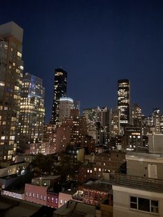 the city skyline is lit up at night with buildings in the foreground and lights on