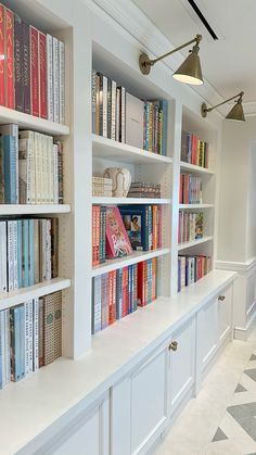 a row of white bookshelves filled with lots of books