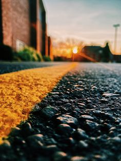 the sun shines brightly behind a building on an empty street with rocks and gravel