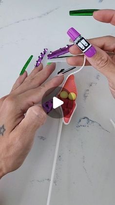 two hands are holding toothbrushes and an object is being made out of paper