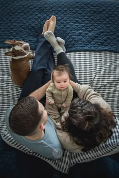 a man and woman laying on top of a bed with a baby in their lap