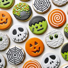 halloween decorated cookies arranged on top of each other in various shapes and colors, including green, orange, black, and white