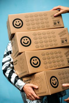 a person holding three boxes with smiley faces on them