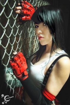 a woman wearing red gloves leaning against a fence