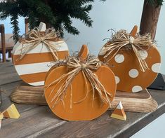 three pumpkins sitting on top of a wooden table