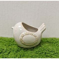 a white ceramic bird shaped planter sitting on green grass