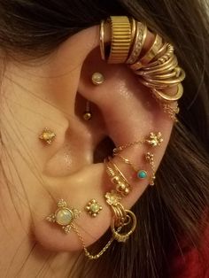 a woman with multiple ear piercings and gold rings on her left ear, all in different designs