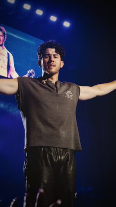 a man holding his arms out while standing on stage