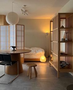 a room with a bed, table and chairs in it next to a book shelf