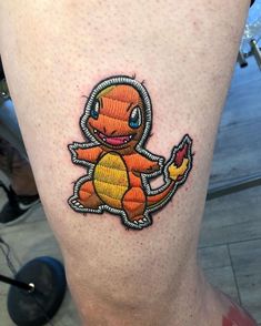 a small tattoo on the leg of a person with an orange and yellow pokemon character