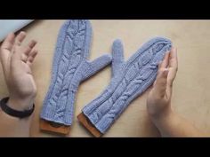 two hands are holding blue knitted mittens