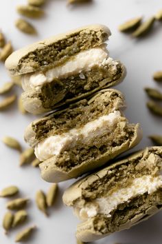 there are four cookies with cream fillings on top of each other and some pistachio seeds around them