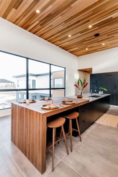 a kitchen with two stools and an island in front of large windows that overlook the water