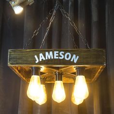 three light bulbs are hanging from a chandelier with the name jameson on it