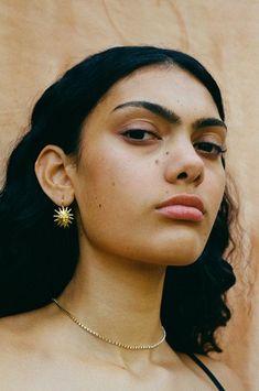 a close up of a person wearing a necklace and earring with a star on it