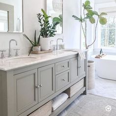 a large bathroom with two sinks and plants on the counter top in front of it