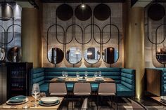 a restaurant with blue booths and round mirrors on the wall, along with wooden tables