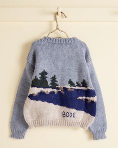 a blue sweater with trees on it hanging from a hook