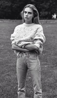 black and white photograph of a woman standing in the grass with her arms crossed looking at the camera