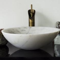 a white marble bowl sink sitting on top of a counter next to a faucet